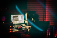 a person sitting at a desk in a recording studio